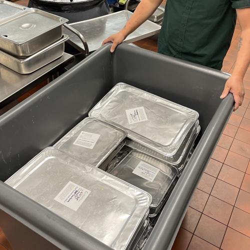 St Paul Public Schools Prepared Food Donation Person pushing cart of foil-covered pans of food