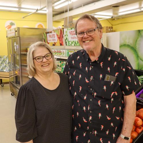 Doug and Diane at ACBC Food Shelf A man and woman posing in glasses and black shirts in a food shelf