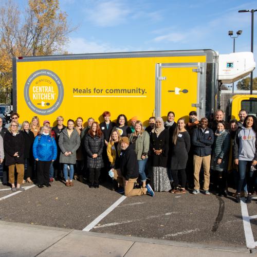 A group of people pose in front of a yellow MCK truck