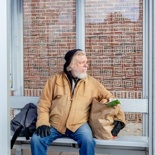 Man with groceries at a bus stop