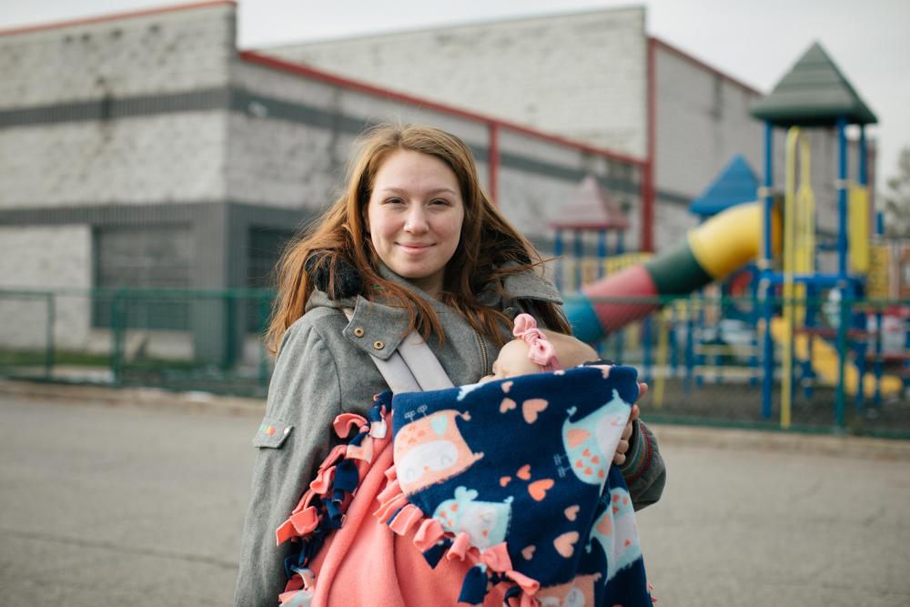 A woman with a baby smiles at the camera