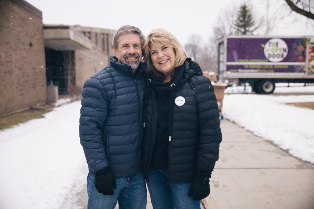 An older couple volunteers outside at winter food distribution