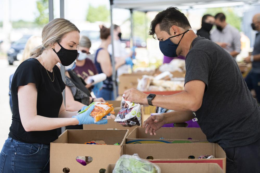 Two people packing food into boxes during distribution