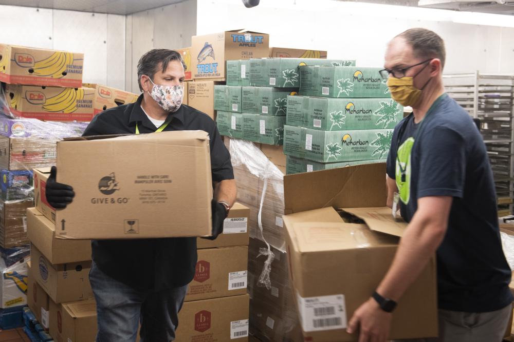 Two people carry boxes of food