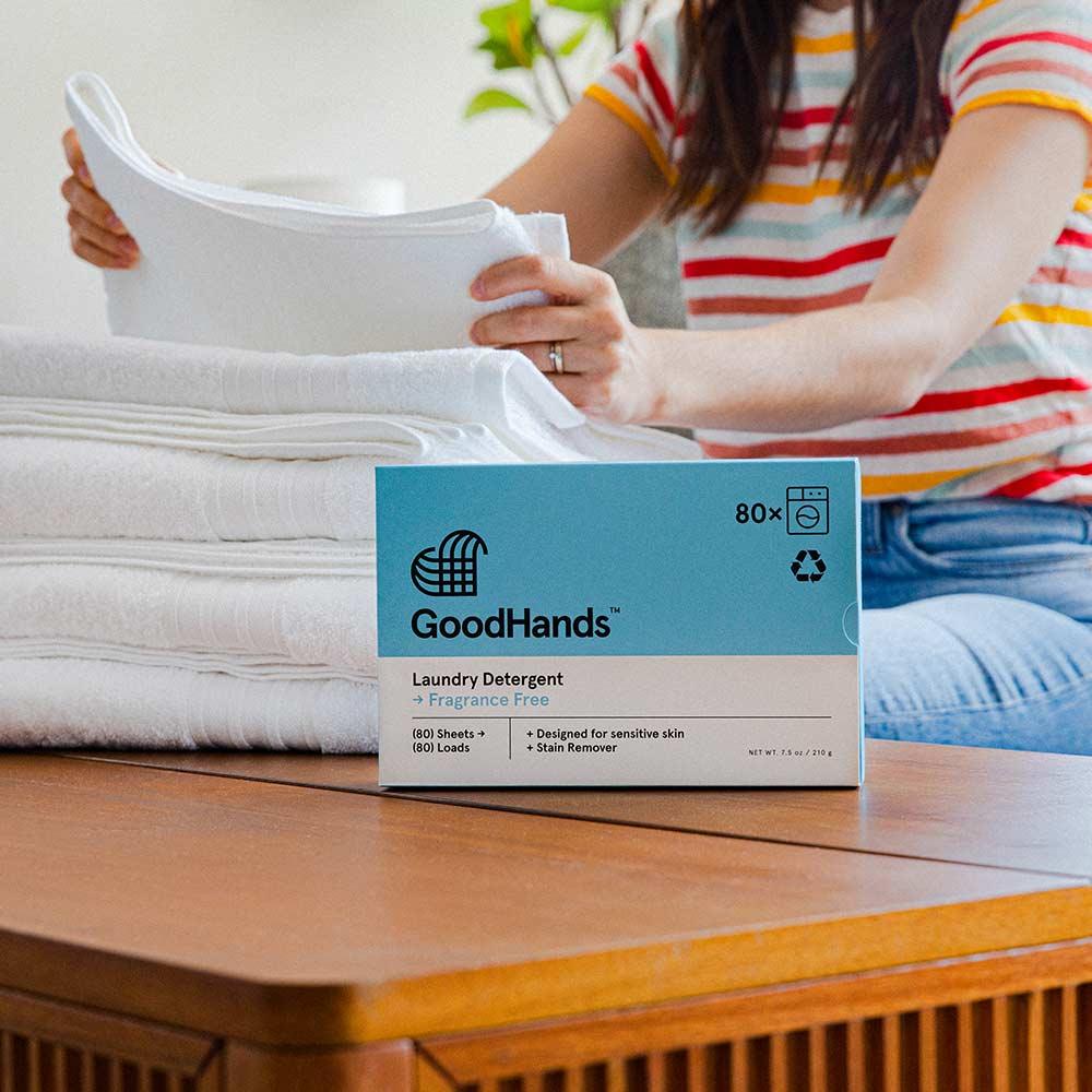 woman folding towels with laundry detergent sheets displayed