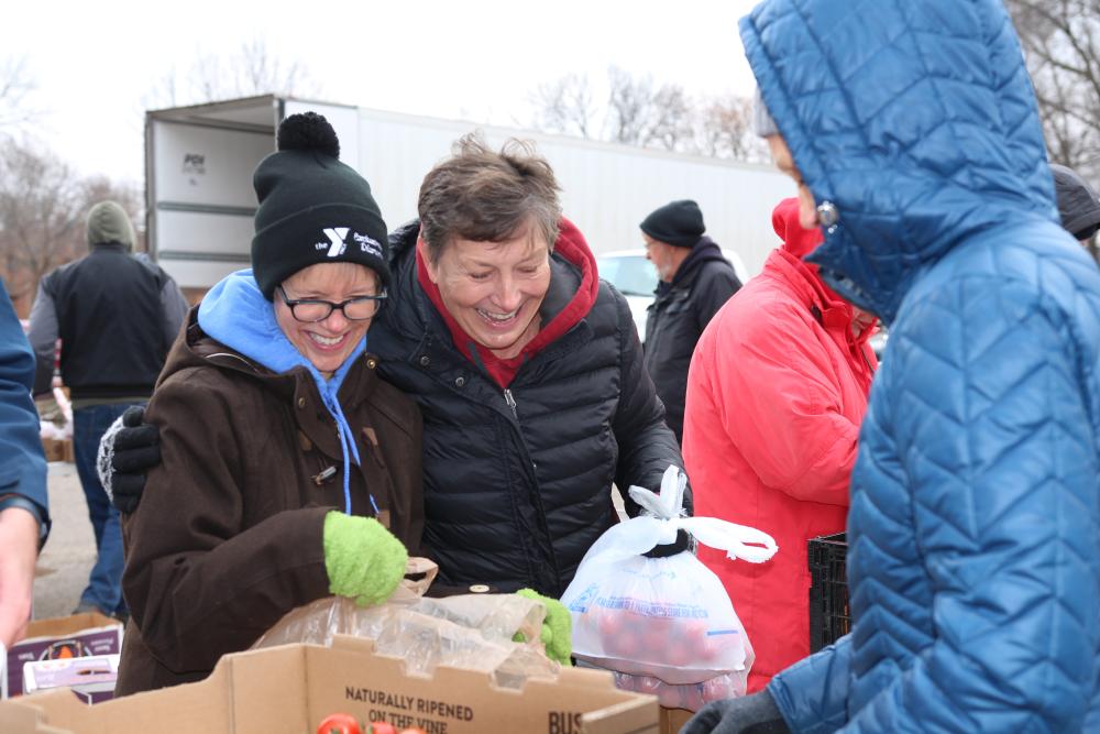 Food shelf volunteers place groceries in plastic bags outside in winter