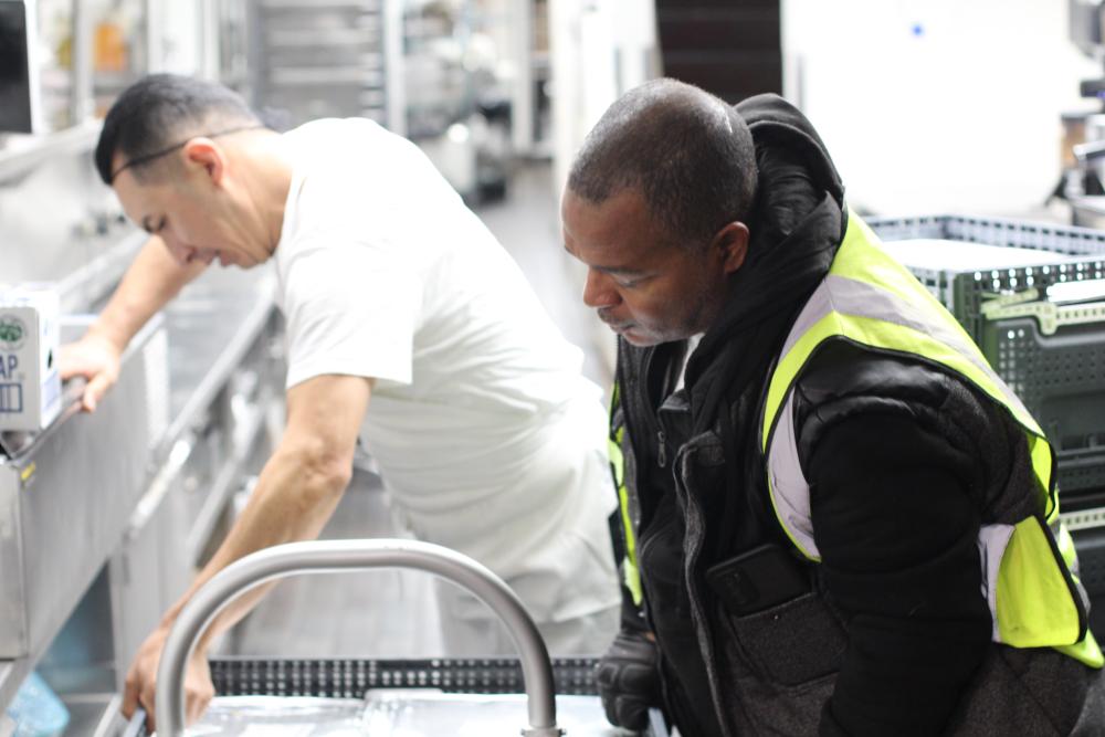 Two men load a cart with meals