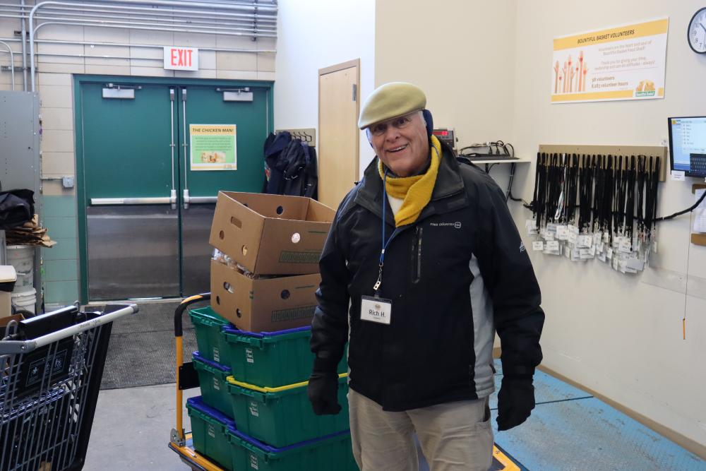 A man in a hat and coat standing next to a stack of bins