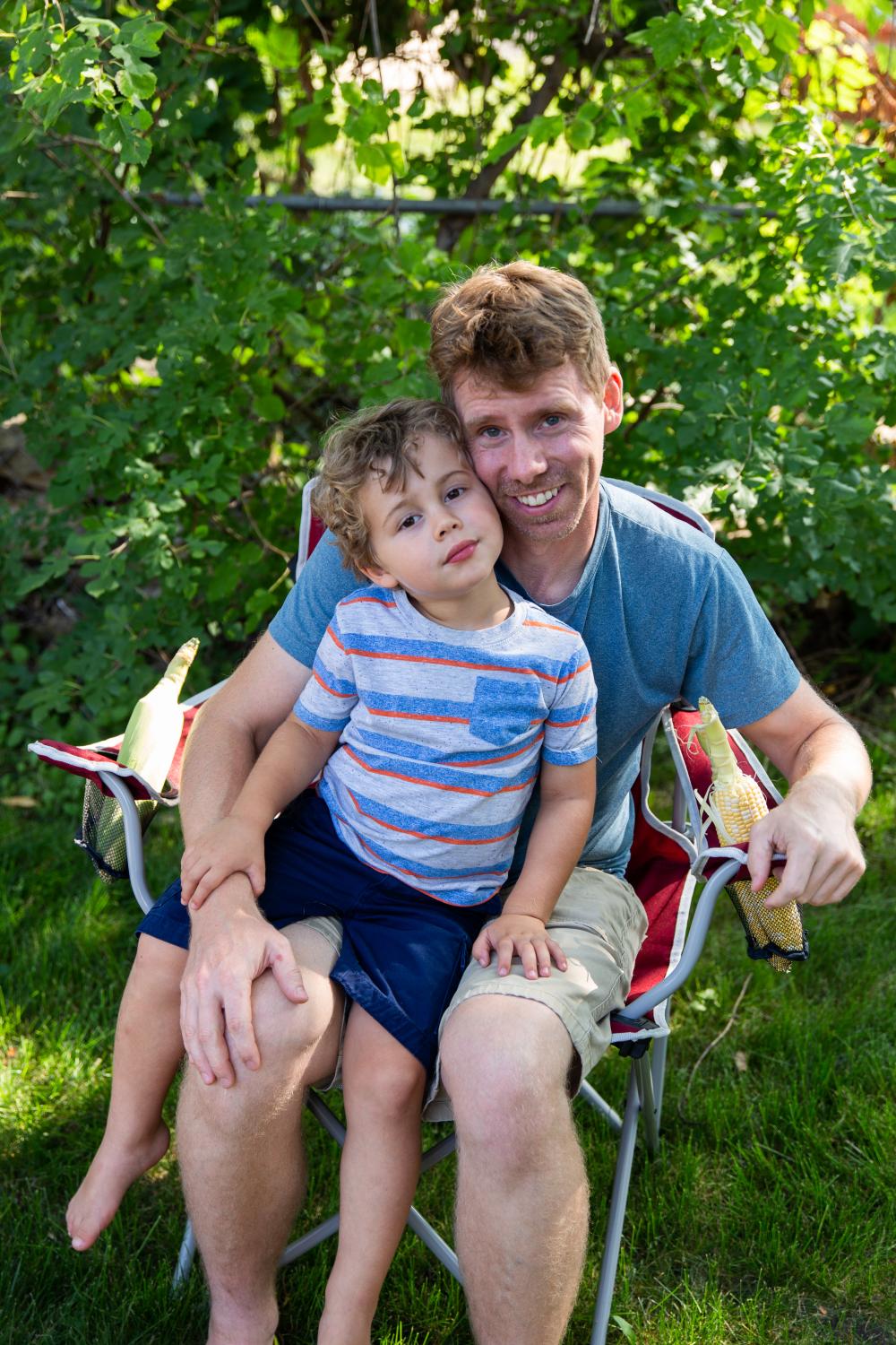 A man and child sitting outside in a chair