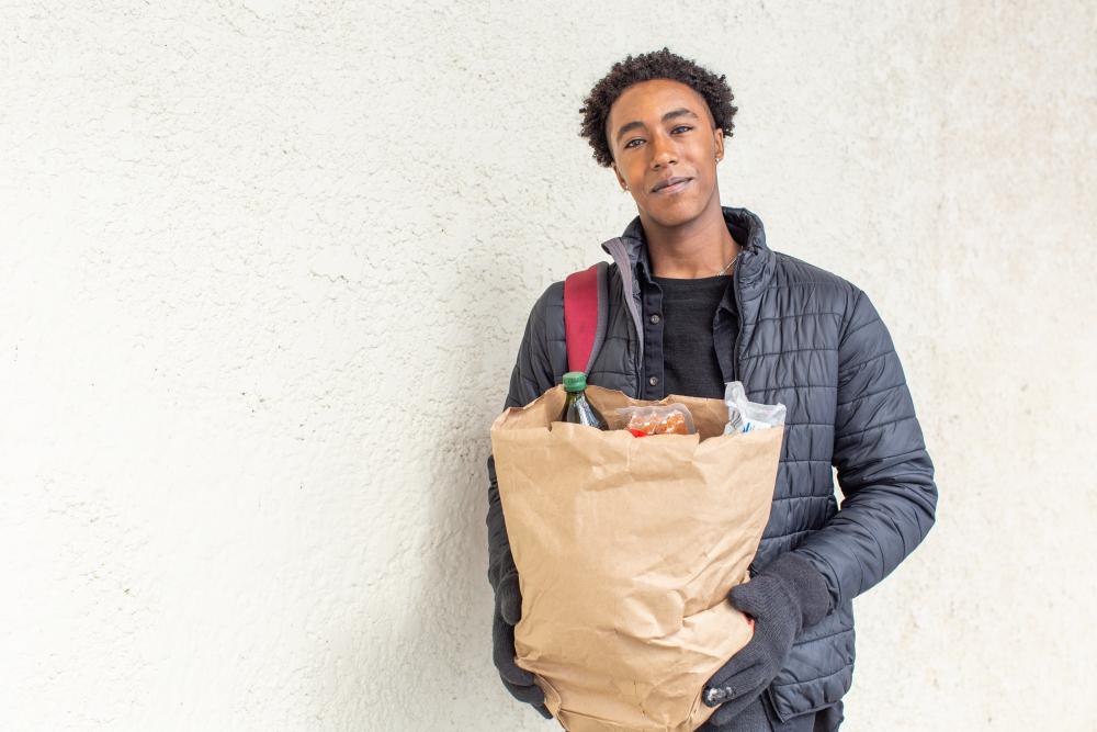 A person standing outside, holding a bag of groceries