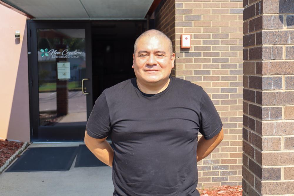 A man in a black shirt stands outside a food shelf