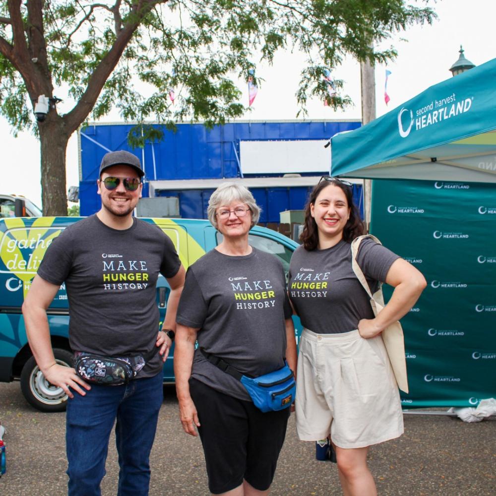 Three people standing outside, wearing Make Hunger History t-shirts