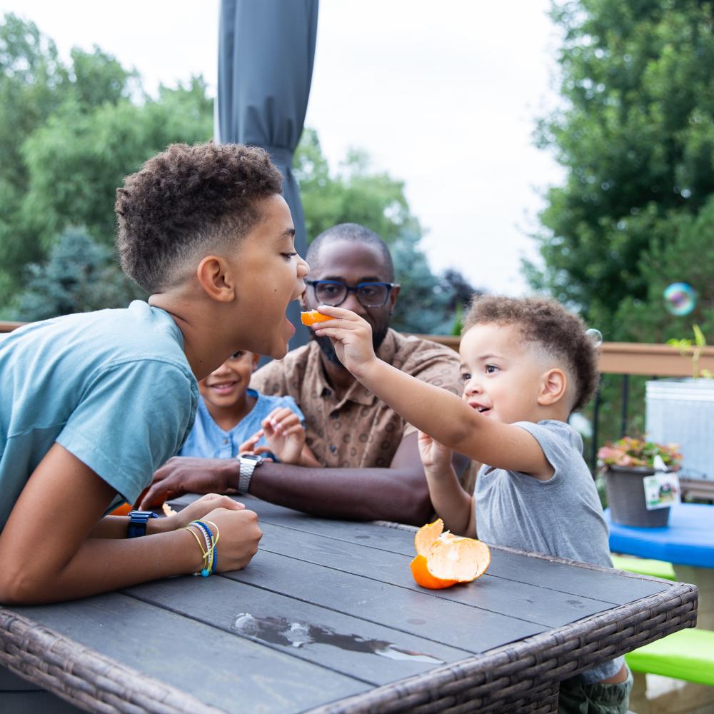 A family sitting outdoors, sharing food