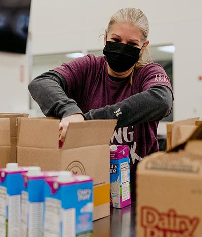 A volunteer packs FOODRx boxes