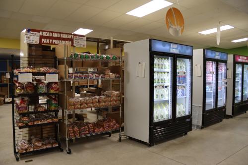 A cooler full of dairy products next to a shelf full of bread.