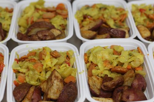 White trays filled with potatoes and cooked vegetables