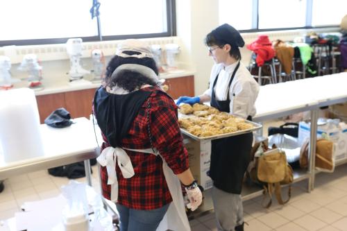 Two chefs carry a tray of chicken