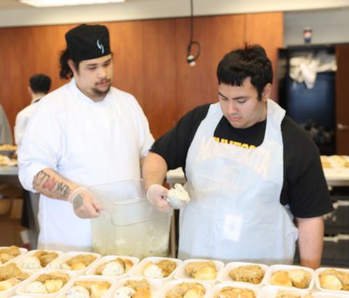 Two chefs scooping coleslaw 